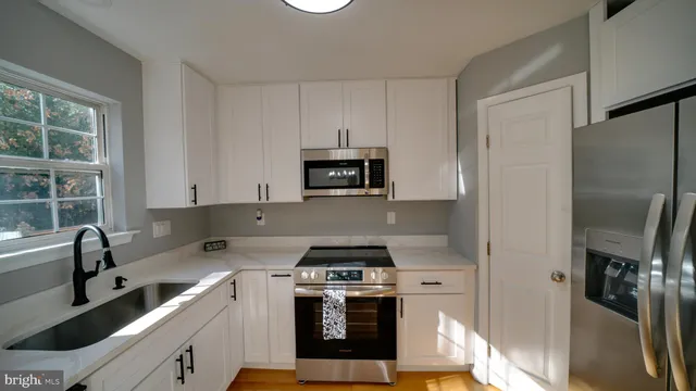 a view of kitchen with stainless steel appliances wooden floor and window