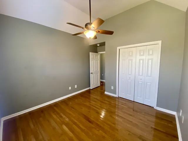 an empty room with wooden floor exposed radiator and windows