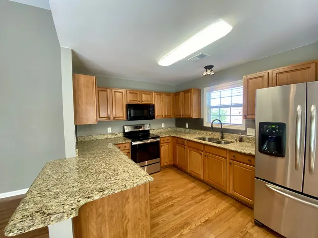 a kitchen with granite countertop a sink a counter space and wooden floor