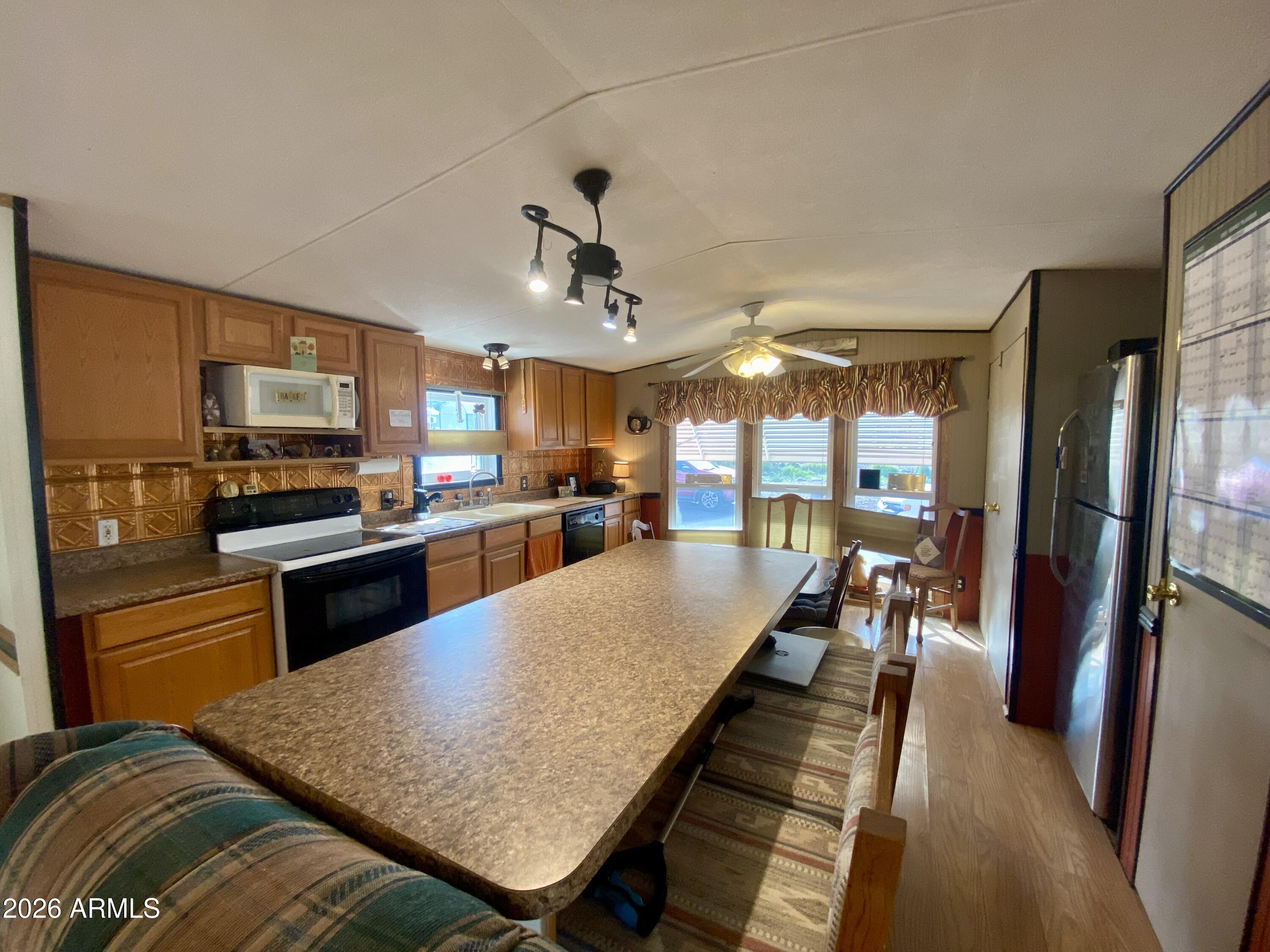723 Finnie Flat Road, Unit 103 Camp Verde, AZ 86322 - Photo 13 of 41 a kitchen with stainless steel appliances granite countertop a refrigerator a stove top oven a sink dishwasher and white cabinets with wooden floor