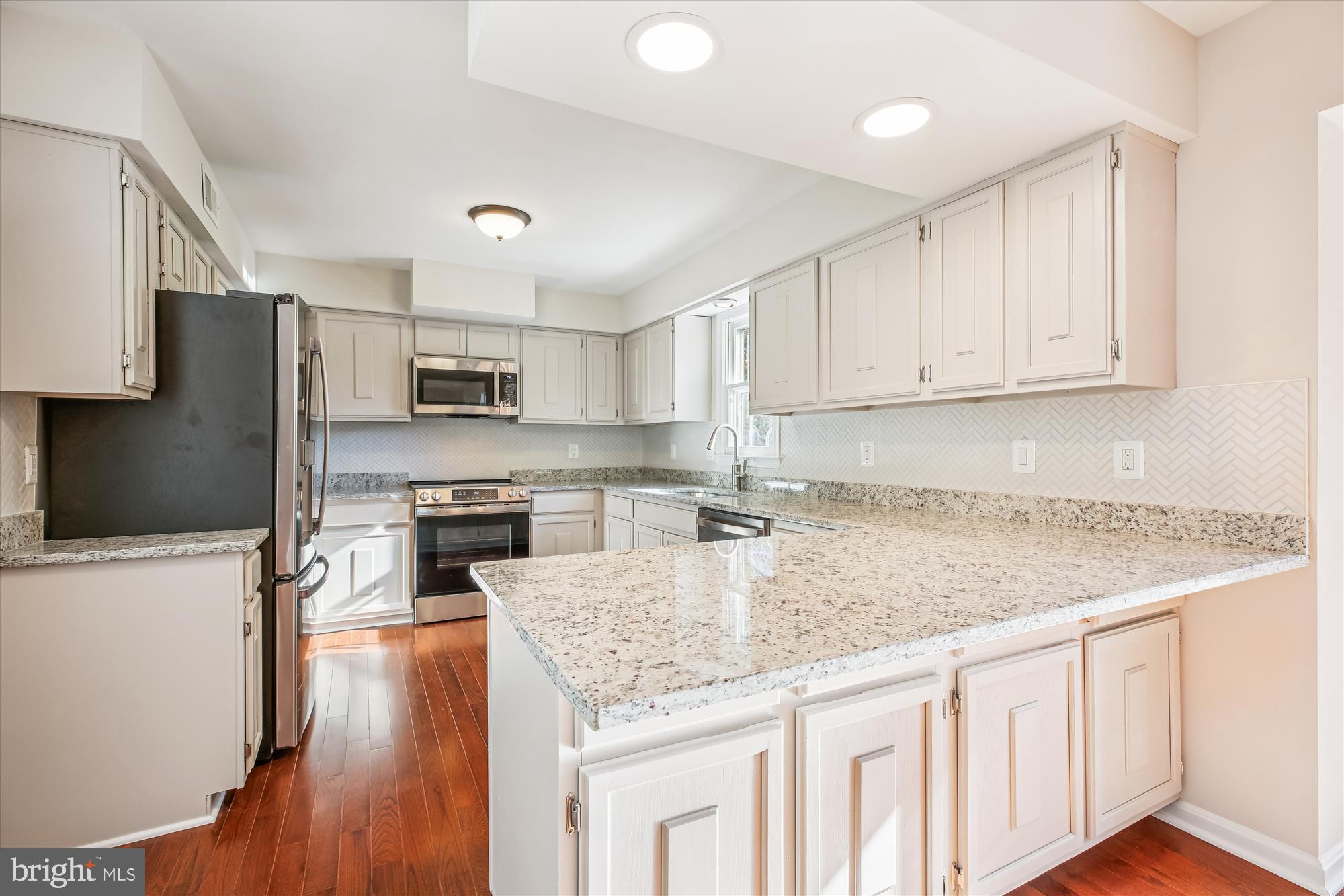 17 Locustwood Court Silver Spring, MD 20905 - Photo 20 of 72 a kitchen with kitchen island granite countertop a sink a stove a refrigerator cabinets and wooden floor