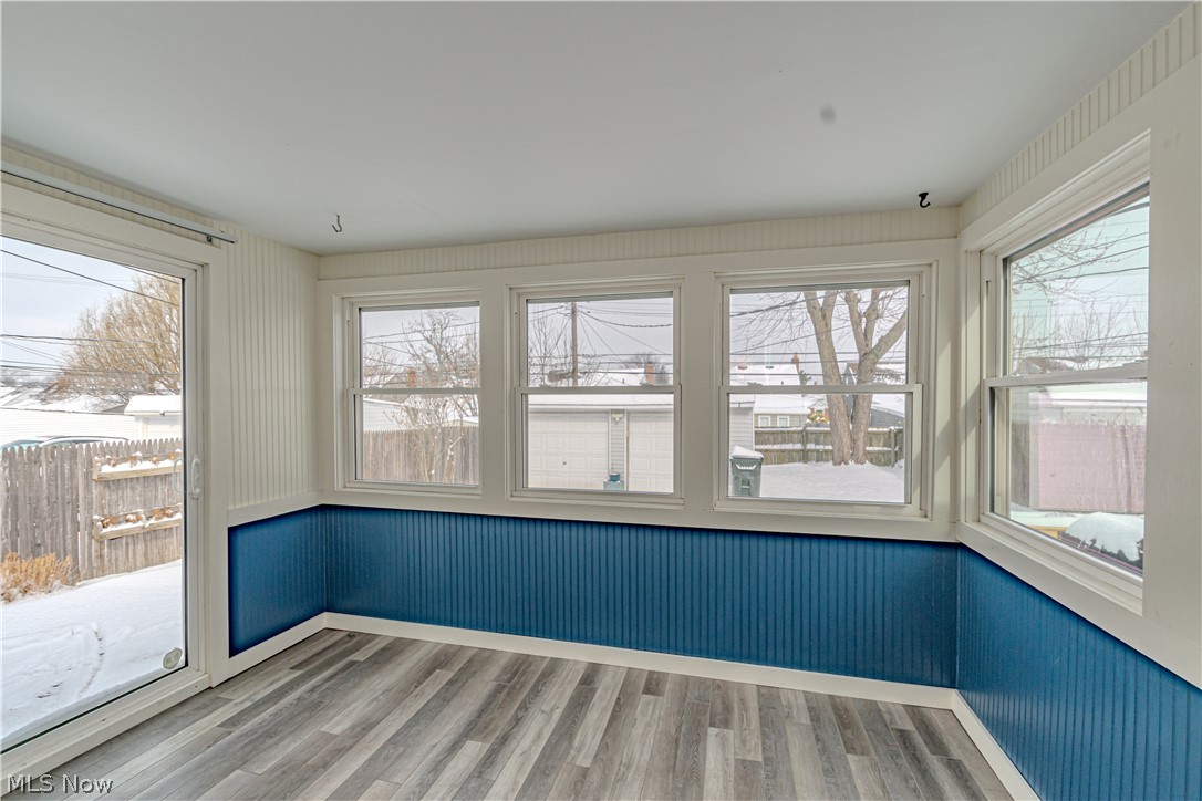 4157 Verona Road Cleveland, OH 44121 - Photo 17 of 26 Unfurnished room with wainscoting, light wood-type flooring, plenty of natural light, and wood walls