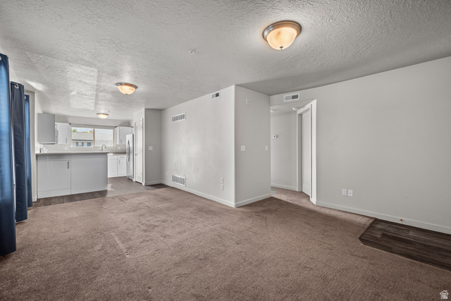 1700 South Sandhill Road West, Unit E 301 Orem, UT 84058 - Photo 3 of 20 Open-concept living area featuring neutral-toned carpet, light gray walls, and two flush-mount ceiling lights