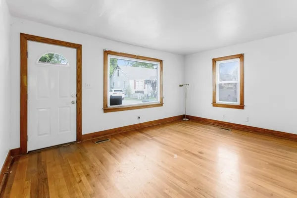 a view of an empty room with wooden floor and a window
