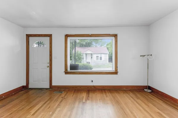 a view of an empty room with wooden floor and a window