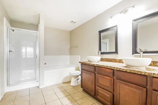 a spacious bathroom with a granite countertop sink toilet mirror and bathtub