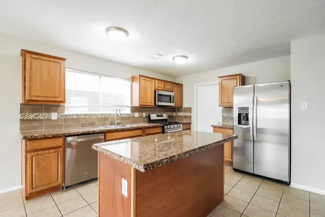 a kitchen with stainless steel appliances granite countertop a refrigerator a stove a sink and a microwave