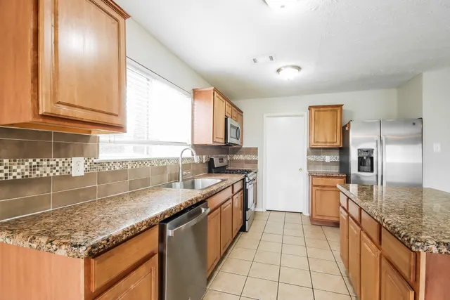a large kitchen with granite countertop a sink and cabinets