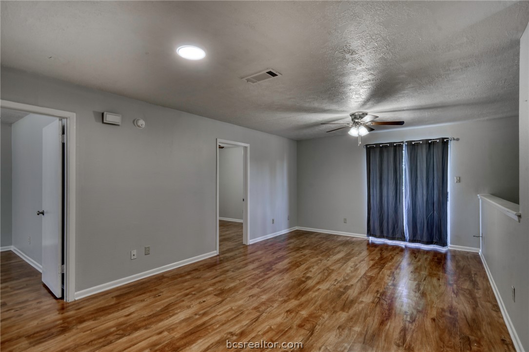 910 Spring Loop, Unit B College Station, TX 77840 - Photo 3 of 11 Empty room with wood finished floors, ceiling fan, and a textured ceiling