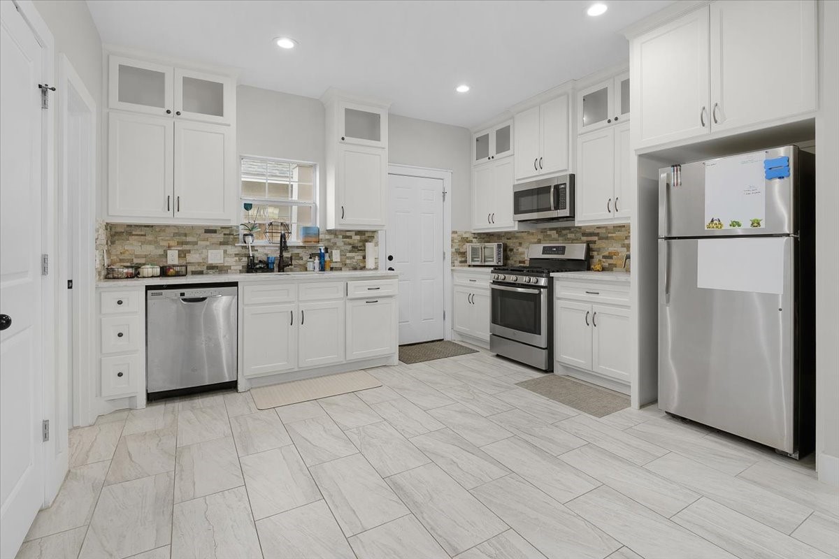 6501 Stratton Street Houston, TX 77023 - Photo 30 of 46 Fresh and minimal open-concept kitchen featuring white cabinetry, stainless steel appliances, and plenty of natural light.