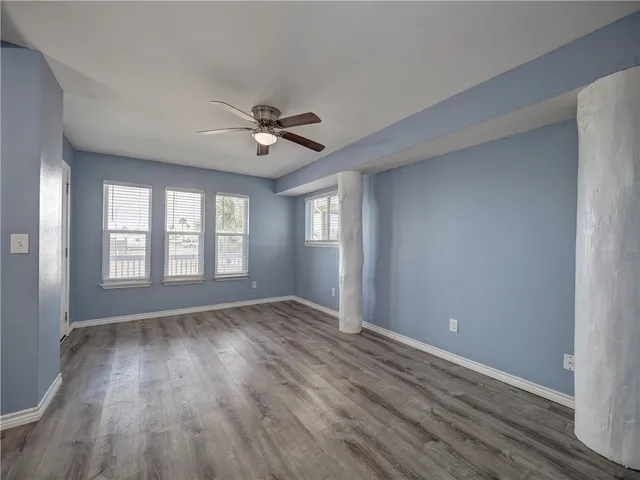 a view of empty room with wooden floor and fan