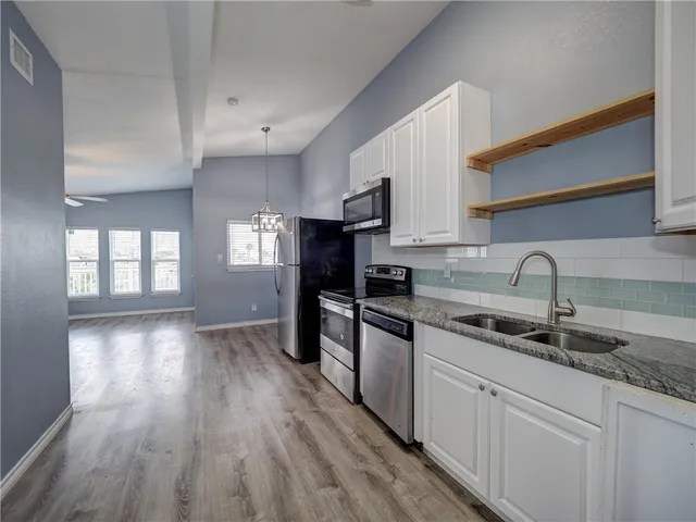 a view of an empty room with wooden floor and window