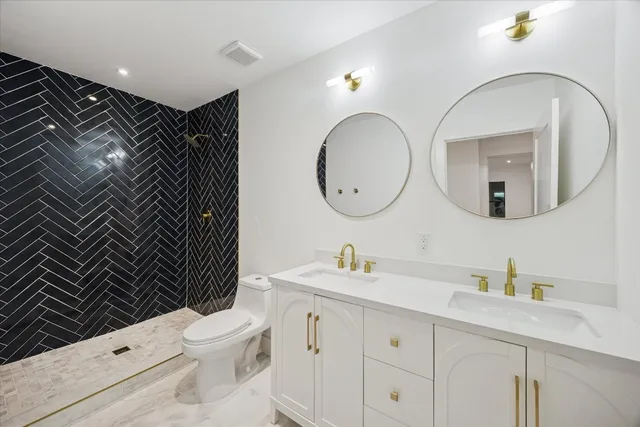 a bathroom with a toilet sink double vanity and mirror