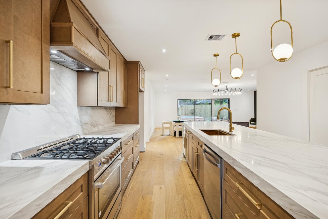 1611 Ridgehaven Drive Austin, TX 78723 - Photo 6 of 35 a large kitchen with stainless steel appliances granite countertop a stove a sink dishwasher and white cabinets with wooden floor