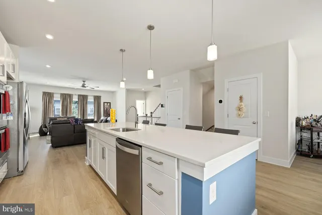 a large kitchen with kitchen island a stove a sink a refrigerator and a dining table with wooden floor