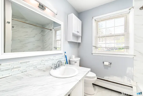 a bathroom with a sink a toilet and a window