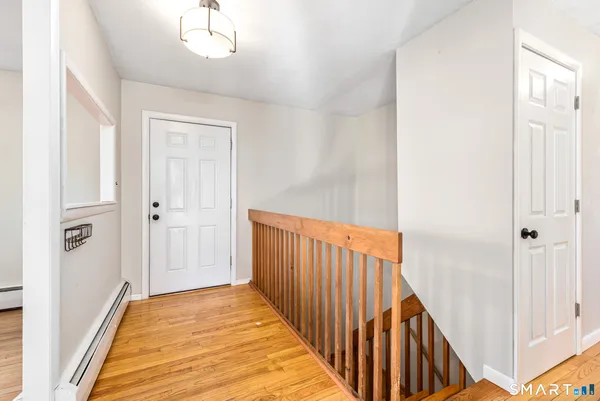 a view of a hallway with wooden floor and staircase