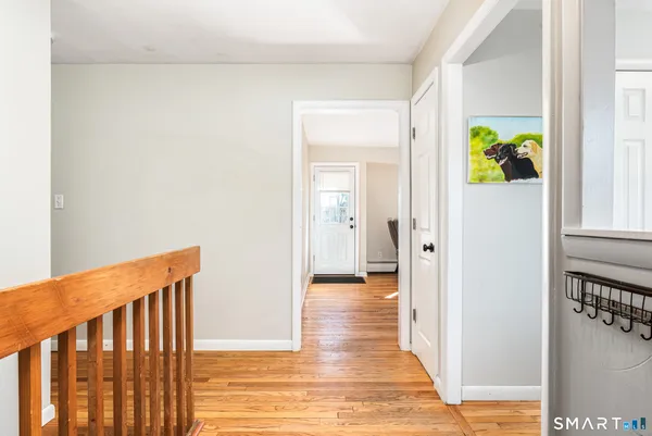 a view of a hallway with wooden floor and a dining room