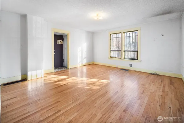 an empty room with wooden floor and windows