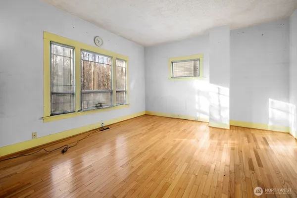 a view of an empty room with wooden floor and a window