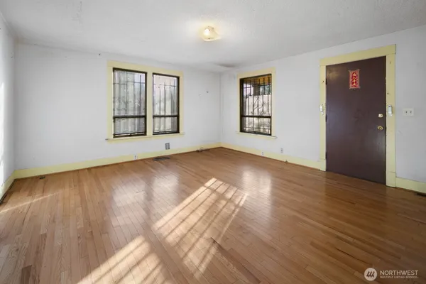a view of an empty room with wooden floor and a window