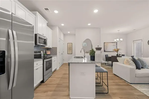 a large kitchen with stainless steel appliances lots of white cabinets and a refrigerator