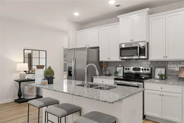a kitchen with kitchen island granite countertop a sink and a stove top oven with wooden floor