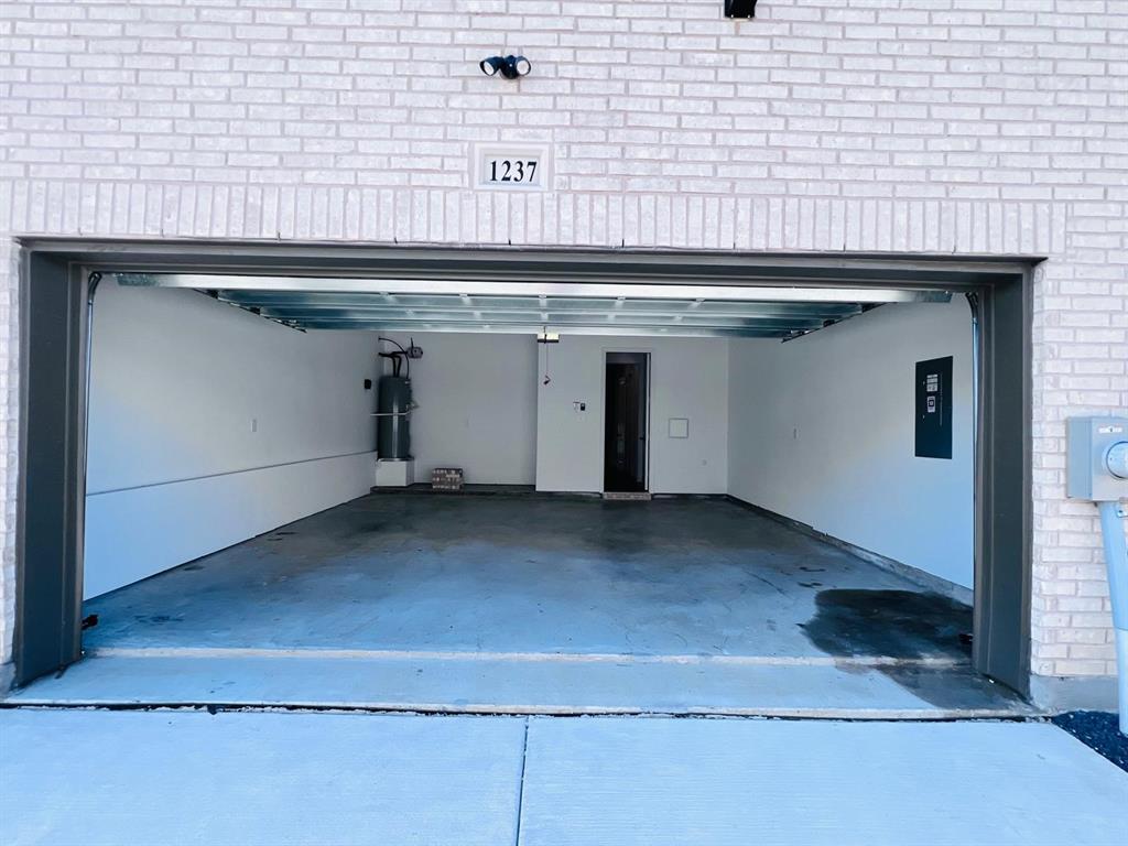 1237 Doris May Drive Allen, TX 75013 - Photo 18 of 19 Spacious garage with light brick exterior, concrete flooring, and an overhead lighting fixture