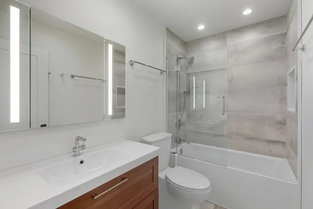 a bathroom with a bathtub shower sink vanity and toilet