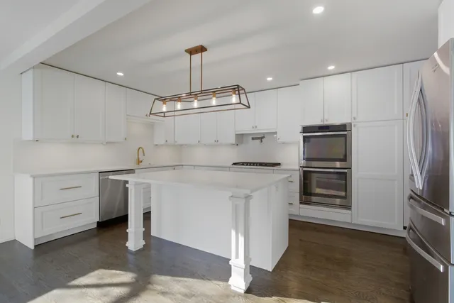 a kitchen with kitchen island white cabinets stainless steel appliances and sink