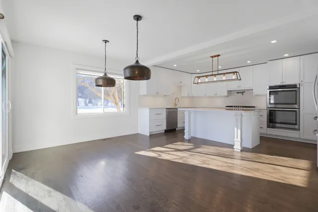 a kitchen with stainless steel appliances granite countertop a sink a stove and a wooden floors
