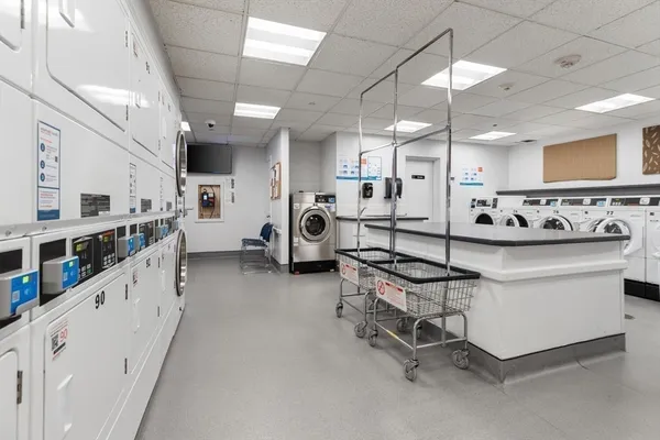 a large white kitchen with stainless steel appliances kitchen island granite countertop lots of white cabinets and wooden floors