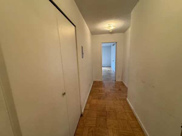 a view of a hallway with wooden floor and a bathroom
