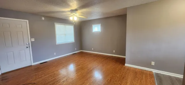 an empty room with wooden floor and windows