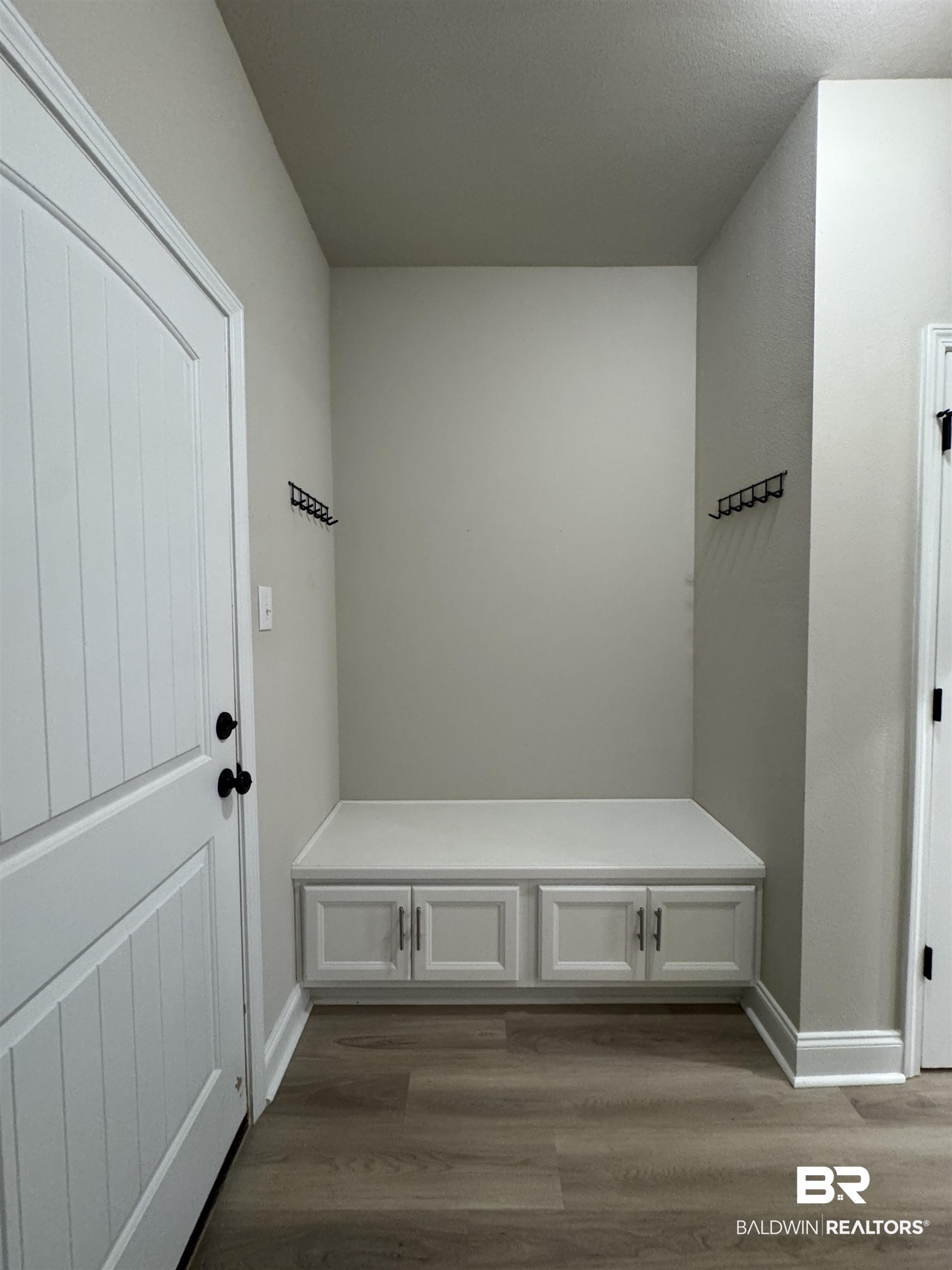 1060 Chloe Street Foley, AL 36535 - Photo 16 of 28 Entryway featuring a built-in bench with cabinet storage, wood-finish flooring, and wall-mounted coat hooks