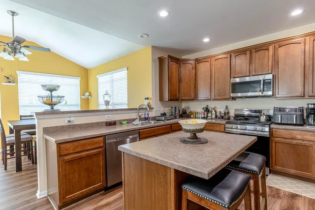 a kitchen with a stove a sink a kitchen island and chairs in it