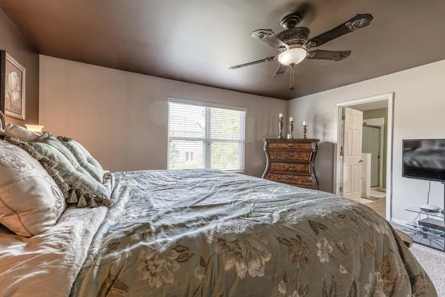 a bedroom with a bed and a flat tv screen on dresser