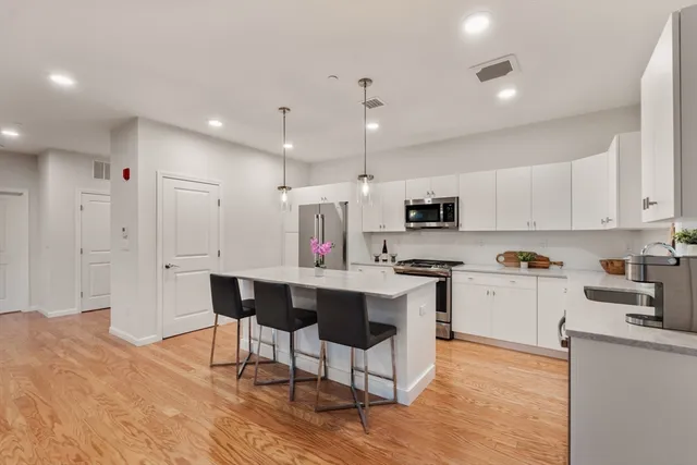 a kitchen with stainless steel appliances kitchen island granite countertop a table chairs sink and cabinets