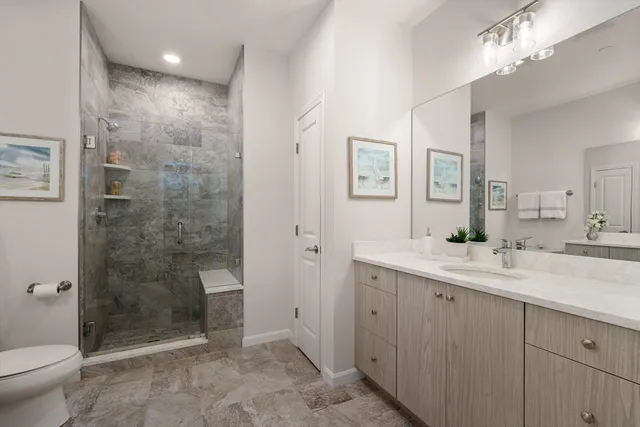 a bathroom with a granite countertop sink a toilet a mirror and shower