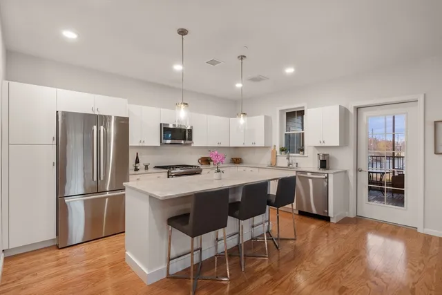 a kitchen with a refrigerator a microwave oven a sink a dining table and chairs