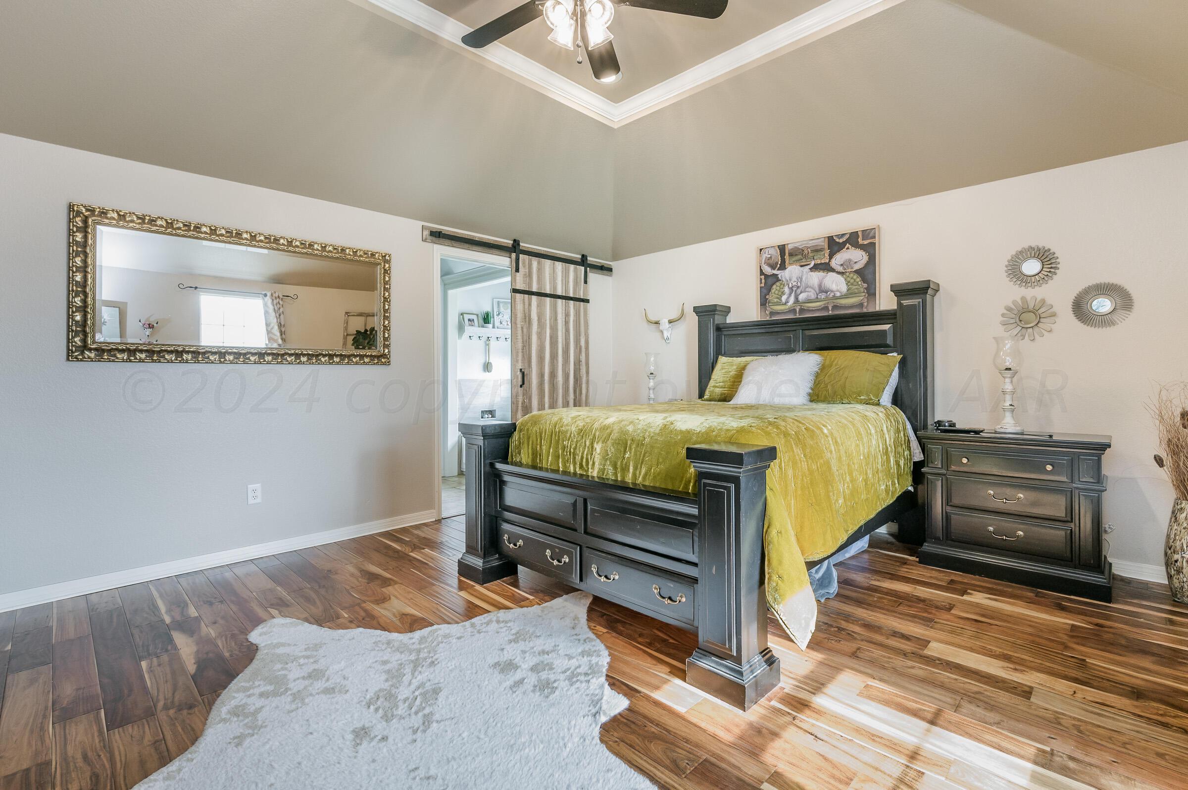 8921 Greyhawk Road Amarillo, TX 79119 - Photo 12 of 56 a bedroom with a bed and a chandelier