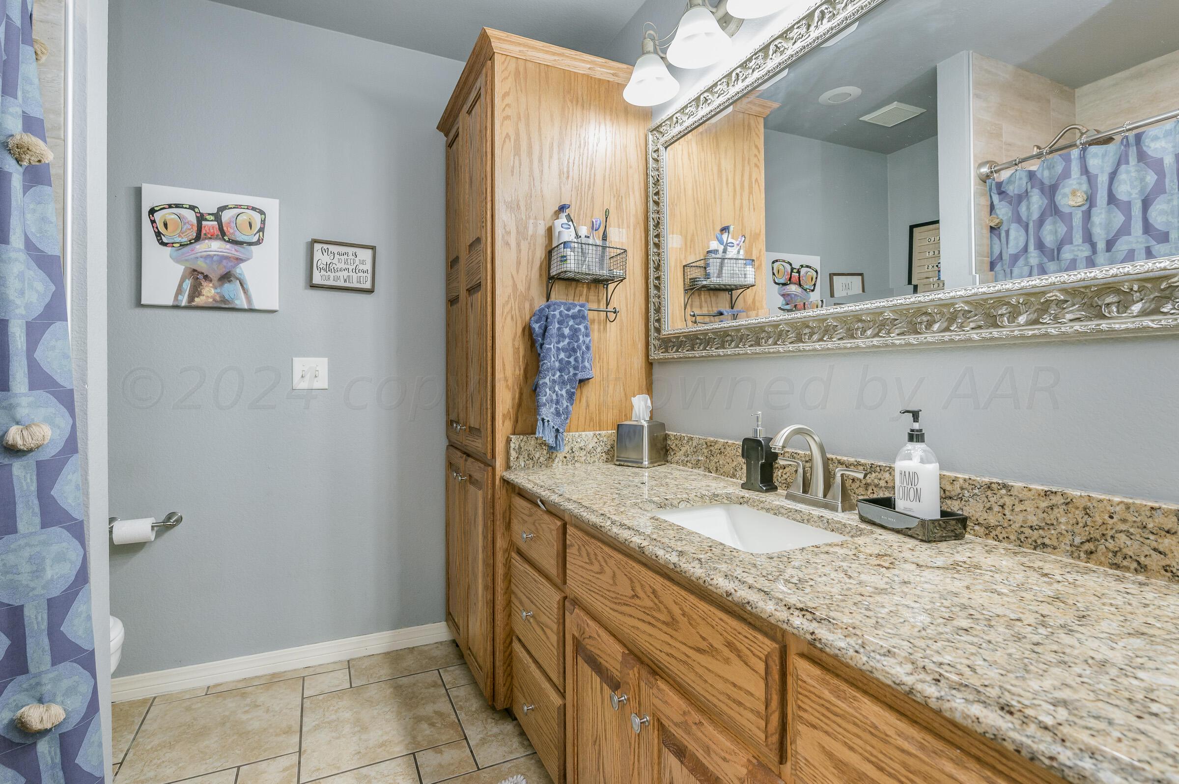 8921 Greyhawk Road Amarillo, TX 79119 - Photo 19 of 56 a bathroom with a granite countertop sink and a mirror