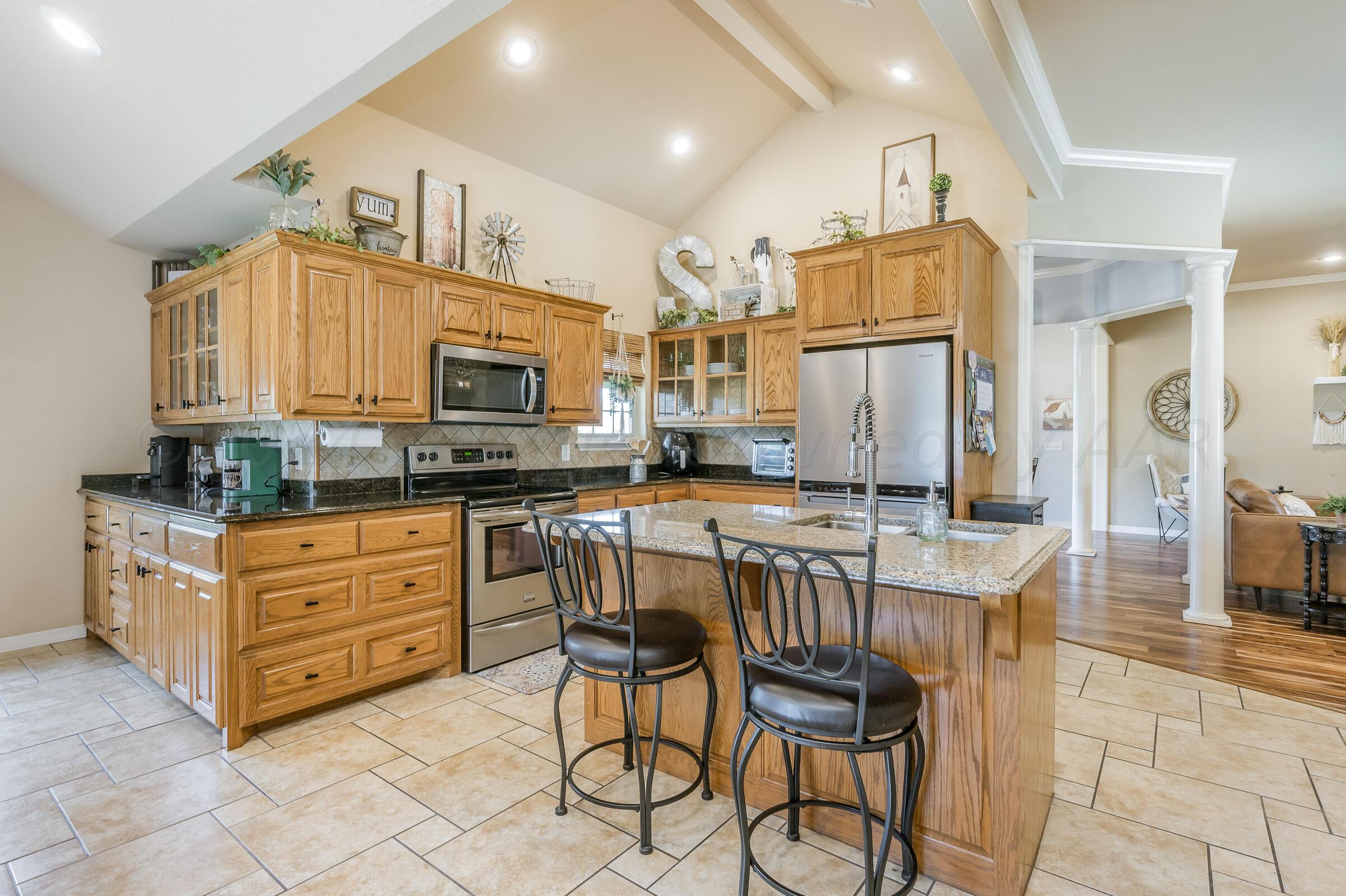 8921 Greyhawk Road Amarillo, TX 79119 - Photo 7 of 56 a kitchen with stainless steel appliances kitchen island granite countertop a stove a sink and a refrigerator