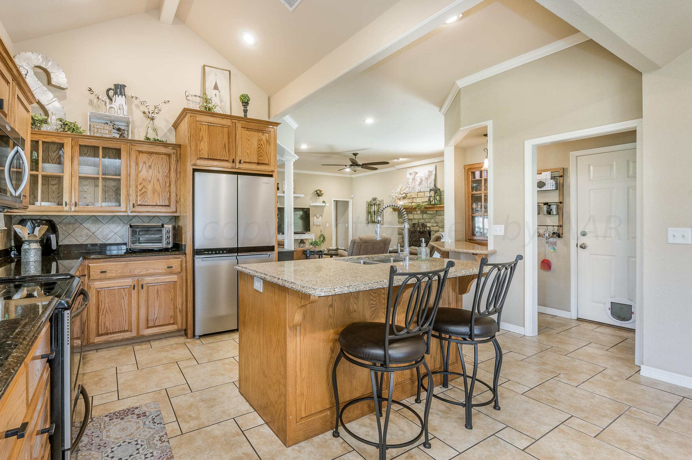 8921 Greyhawk Road Amarillo, TX 79119 - Photo 9 of 56 a kitchen with a table chairs refrigerator and cabinets