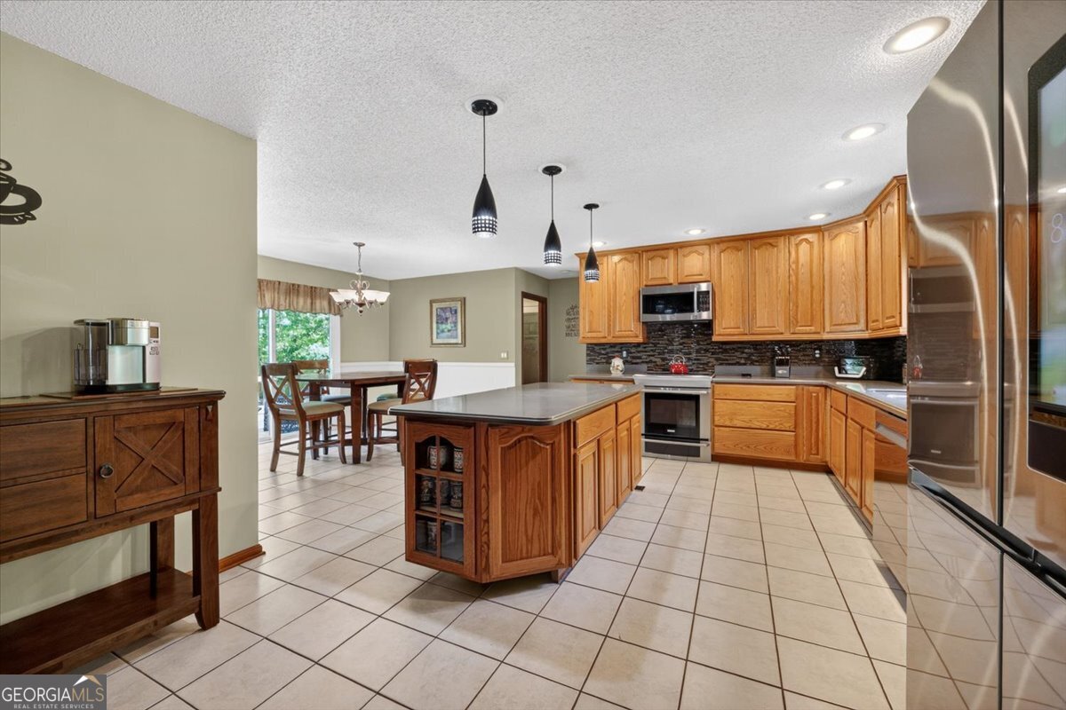 348 Craig Road Forsyth, GA 31029 - Photo 7 of 35 a kitchen with stainless steel appliances granite countertop a stove top oven a sink dishwasher a dining table and chairs with wooden floor
