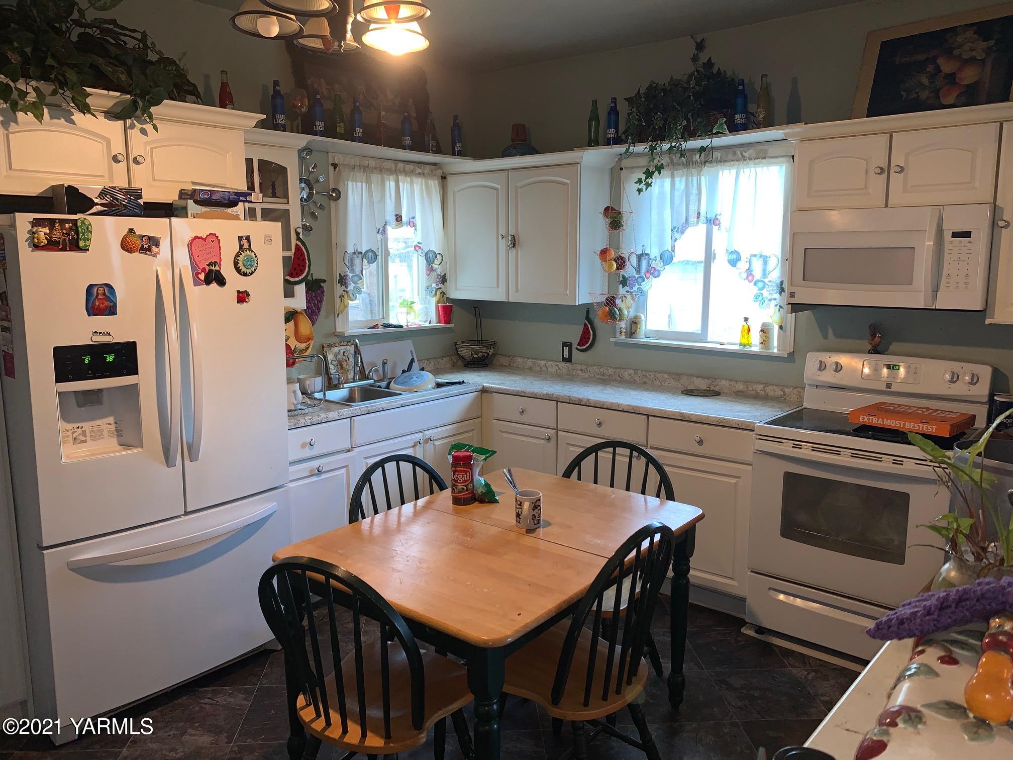 1007 Thornton Road Sunnyside, WA 98944 - Photo 4 of 9 a kitchen with stainless steel appliances a table chairs and a refrigerator