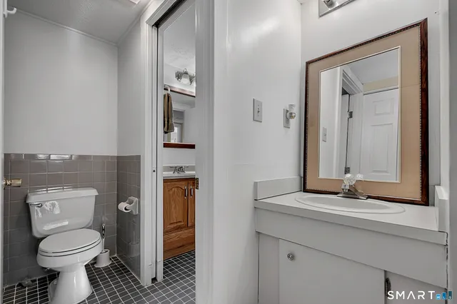 a bathroom with a granite countertop toilet a sink and a mirror