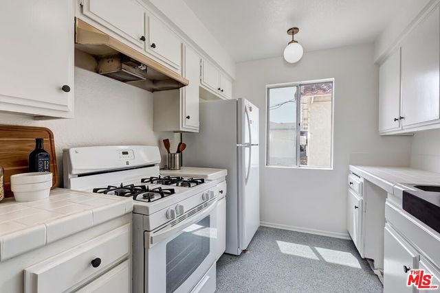 a kitchen with stainless steel appliances a sink a stove and white cabinets