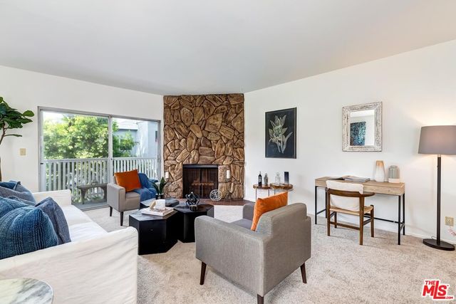 a living room with furniture potted plant a fireplace and a large window