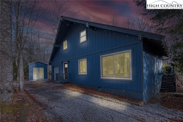 a view of a house with wooden fence and a car parked in front of house